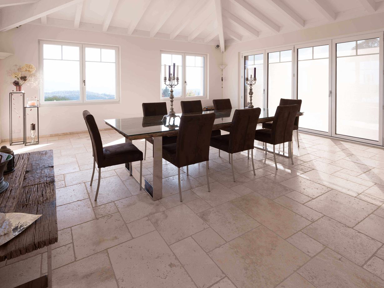 Le sol clair en travertin rend la pièce spacieuse Salle à manger avec table et chaises et au sol un carrelage en travertin Light en format opus romain